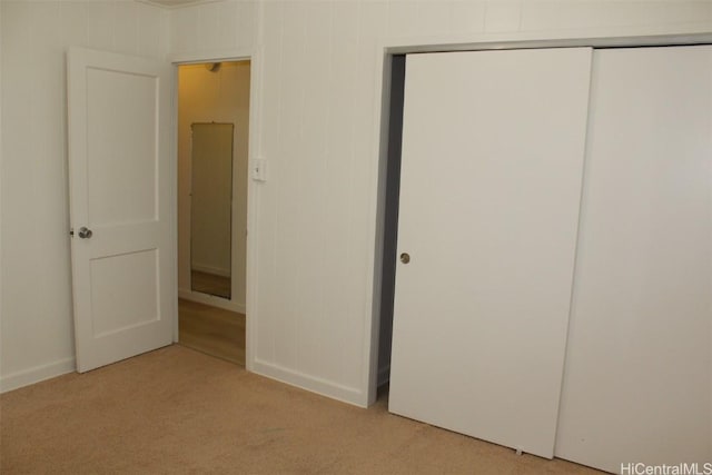 unfurnished bedroom featuring light carpet and a closet