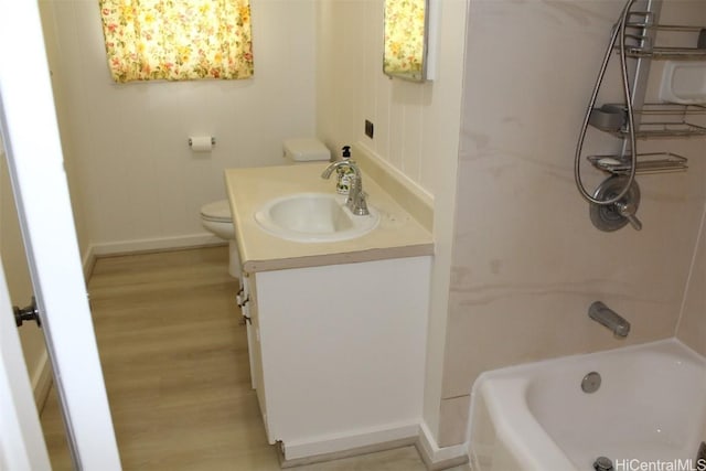 bathroom with a bath, vanity, wood-type flooring, and toilet