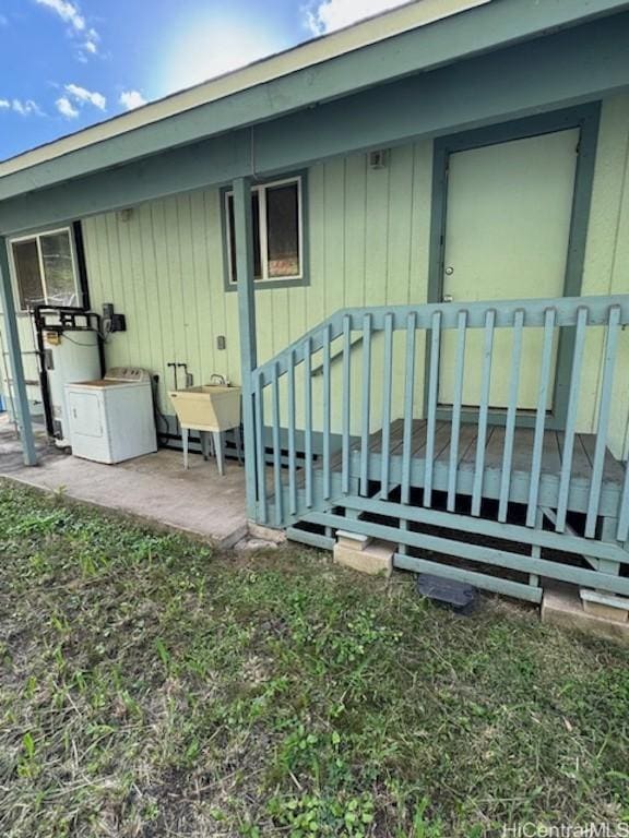 doorway to property with washer / clothes dryer, a deck, water heater, and sink