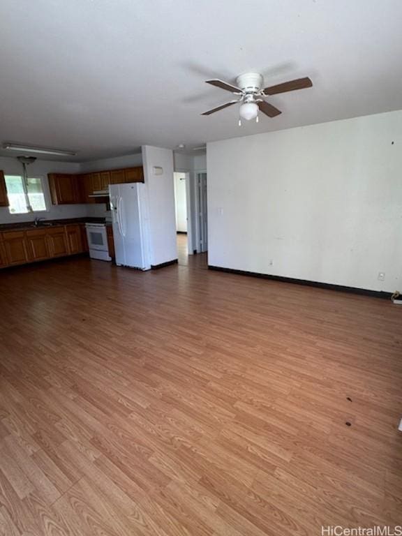 unfurnished living room featuring ceiling fan, sink, and light wood-type flooring