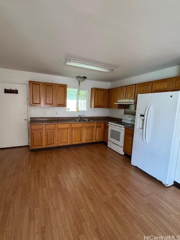 kitchen with white appliances, hardwood / wood-style flooring, and sink