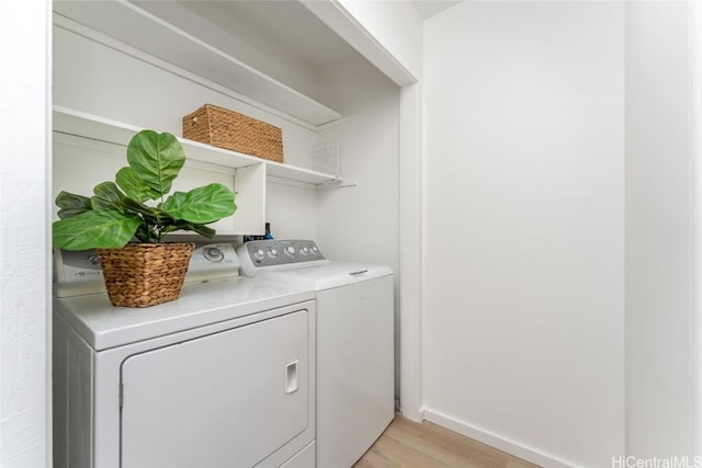 laundry room with washing machine and clothes dryer and light hardwood / wood-style flooring