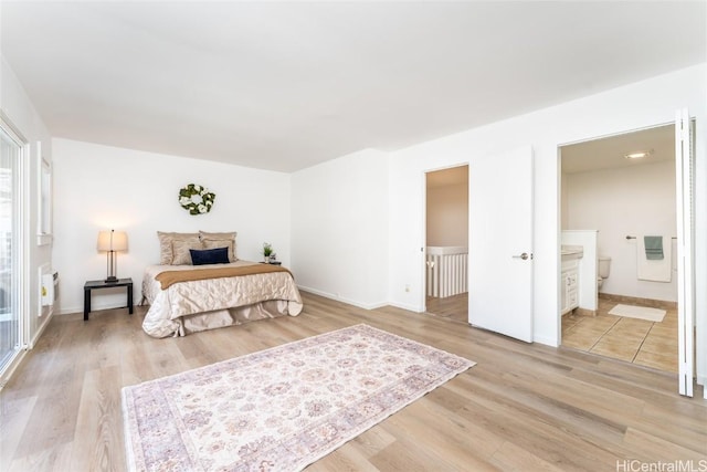 bedroom with connected bathroom and light hardwood / wood-style flooring