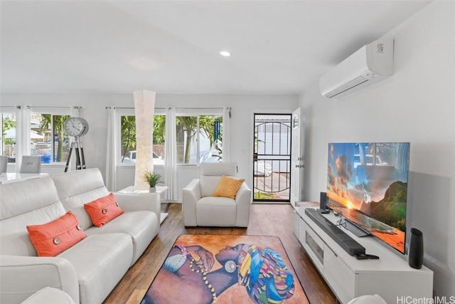 living room with a wall mounted AC, a wealth of natural light, and hardwood / wood-style flooring