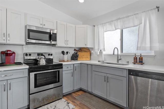 kitchen featuring dark hardwood / wood-style flooring, stainless steel appliances, sink, gray cabinets, and lofted ceiling