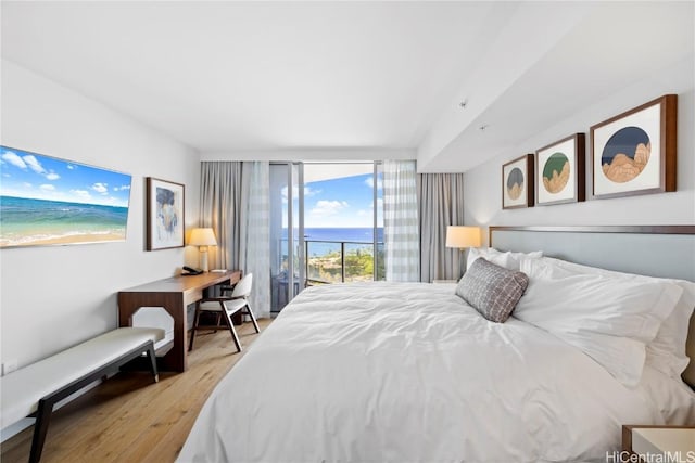 bedroom featuring access to outside, light hardwood / wood-style flooring, and expansive windows