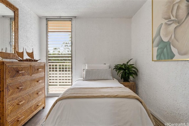 bedroom featuring hardwood / wood-style floors, a textured ceiling, and access to outside