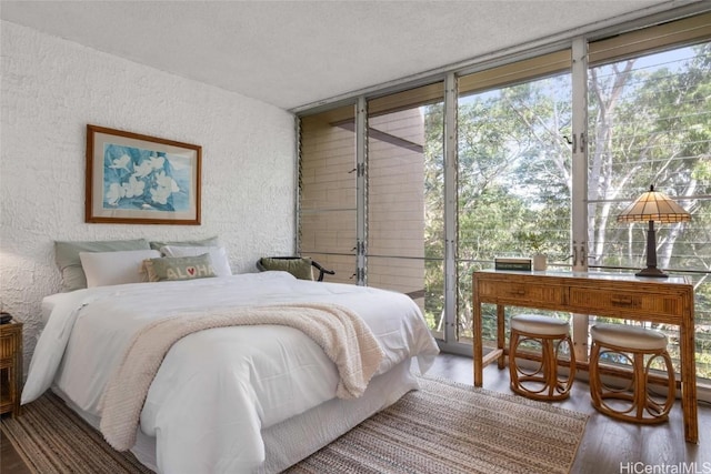 bedroom featuring floor to ceiling windows, a textured ceiling, and hardwood / wood-style flooring