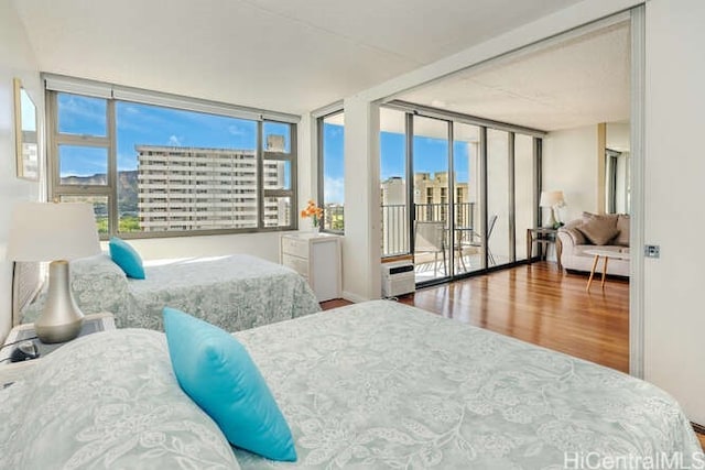 bedroom featuring access to outside, hardwood / wood-style flooring, and a wall of windows