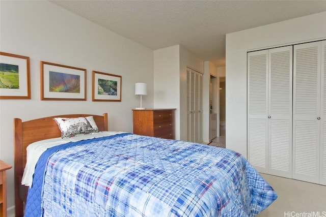 carpeted bedroom featuring a textured ceiling and multiple closets