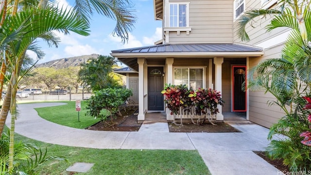 entrance to property featuring a mountain view, a porch, and a yard