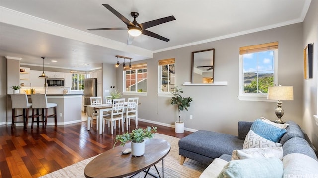 living room featuring plenty of natural light, ceiling fan, ornamental molding, and dark wood-type flooring