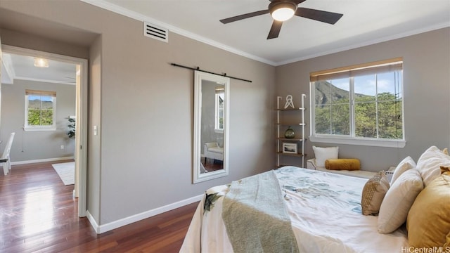 bedroom with a barn door, dark hardwood / wood-style floors, ceiling fan, and crown molding