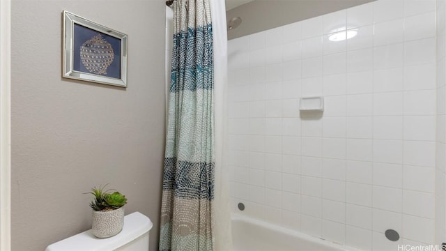 bathroom with shower / bath combination with curtain and toilet