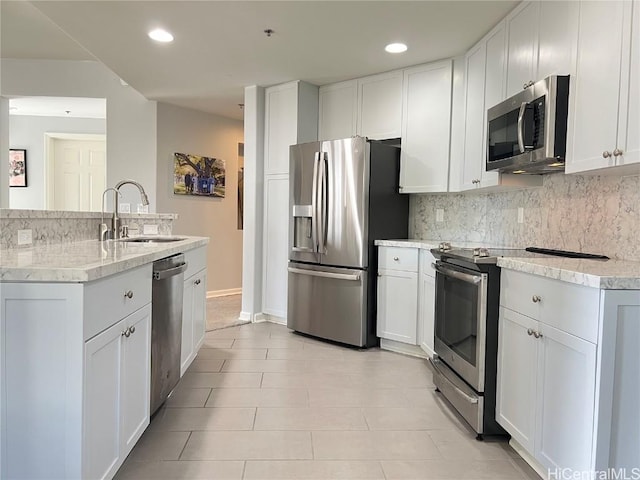 kitchen with sink, stainless steel appliances, light tile patterned floors, decorative backsplash, and white cabinets