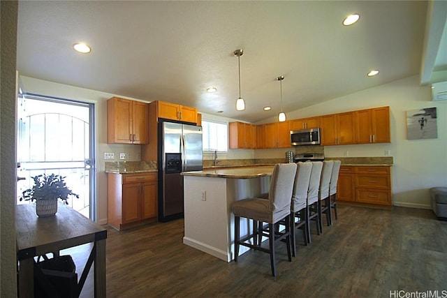 kitchen with vaulted ceiling, pendant lighting, stainless steel appliances, an island with sink, and a kitchen breakfast bar