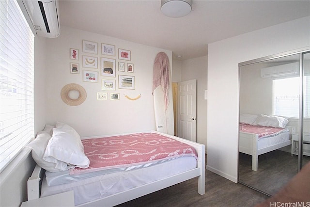 bedroom featuring an AC wall unit, a closet, and dark hardwood / wood-style floors