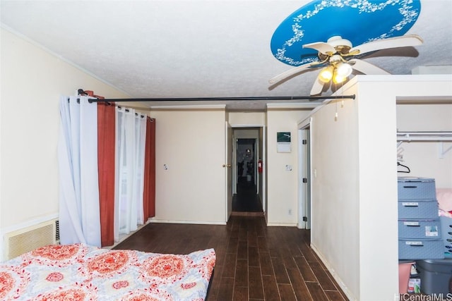 unfurnished bedroom featuring ornamental molding, a textured ceiling, ceiling fan, dark wood-type flooring, and a closet