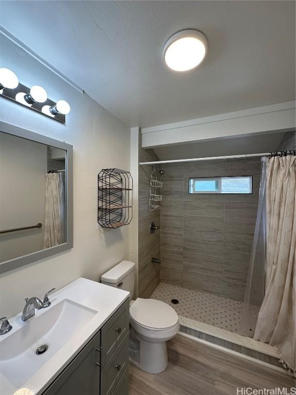 bathroom with vanity, hardwood / wood-style flooring, toilet, and curtained shower