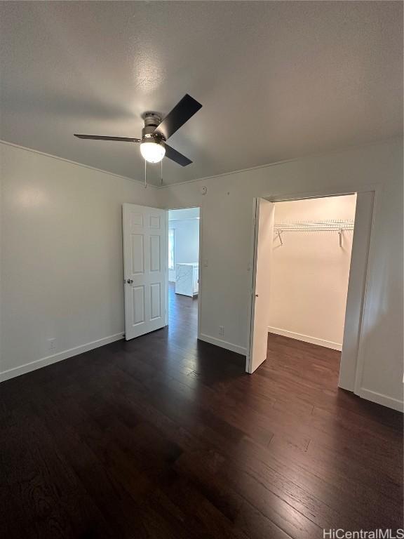 unfurnished bedroom with ceiling fan, dark hardwood / wood-style flooring, a textured ceiling, and a closet