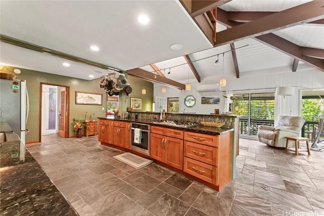 kitchen featuring appliances with stainless steel finishes, hanging light fixtures, beam ceiling, a center island, and dark stone counters