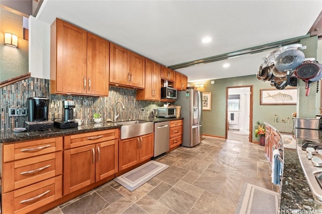 kitchen featuring stainless steel appliances, sink, dark stone countertops, and decorative backsplash