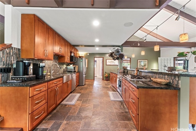 kitchen with decorative backsplash, dark stone counters, sink, and hanging light fixtures