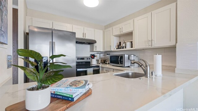 kitchen featuring tasteful backsplash, light stone counters, stainless steel appliances, sink, and white cabinetry