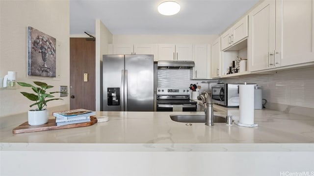 kitchen with light stone countertops, stainless steel appliances, white cabinetry, and sink