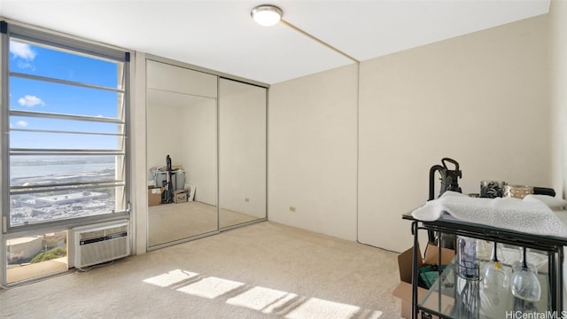 carpeted bedroom featuring a wall mounted air conditioner, a closet, and multiple windows