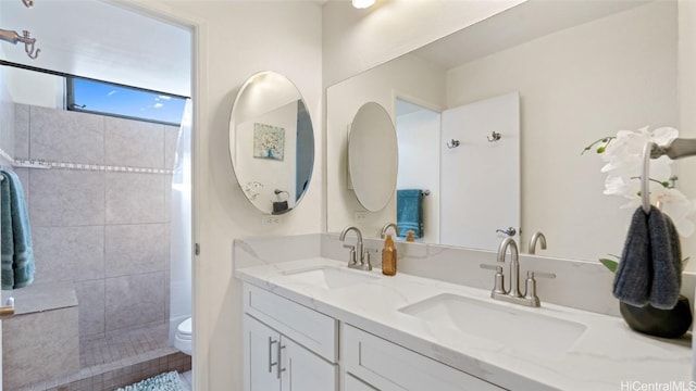 bathroom featuring a tile shower, vanity, and toilet