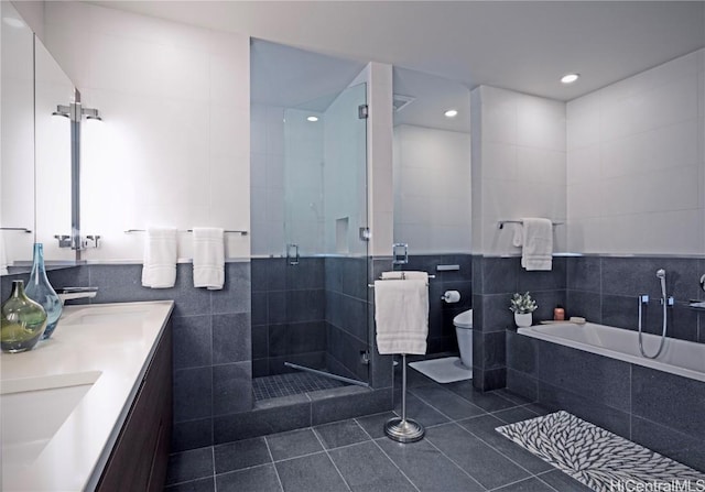 bathroom with double vanity, tile patterned floors, a garden tub, a shower stall, and tile walls