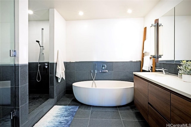 bathroom with tile walls, a shower stall, vanity, tile patterned flooring, and a freestanding tub