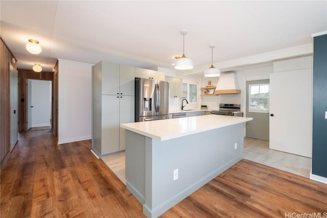 kitchen featuring premium range hood, hanging light fixtures, light hardwood / wood-style flooring, and stainless steel appliances