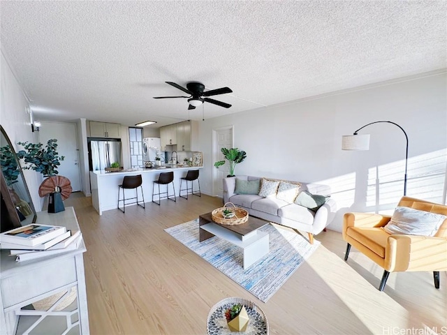 living room with ceiling fan, light hardwood / wood-style floors, and a textured ceiling