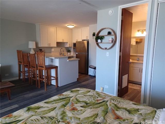 kitchen featuring a breakfast bar, sink, dark hardwood / wood-style floors, white cabinetry, and stainless steel appliances