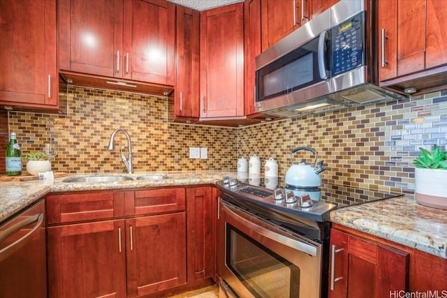 kitchen with light stone countertops, appliances with stainless steel finishes, and tasteful backsplash