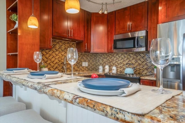 kitchen with decorative backsplash, hanging light fixtures, stainless steel appliances, and light stone counters