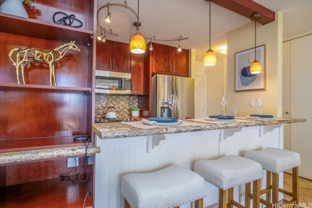 kitchen with decorative backsplash, pendant lighting, a textured ceiling, and appliances with stainless steel finishes