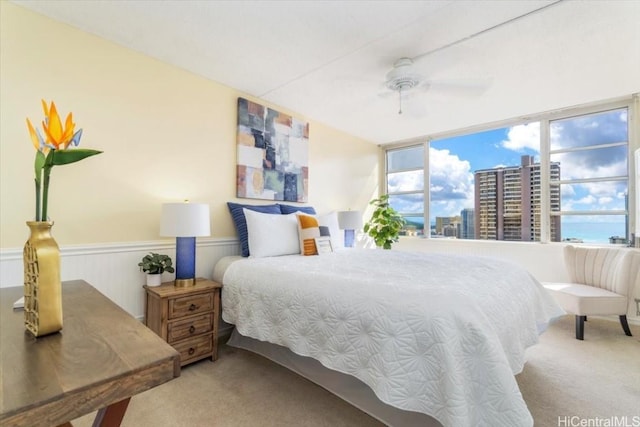 bedroom featuring ceiling fan, a water view, light carpet, and wood walls