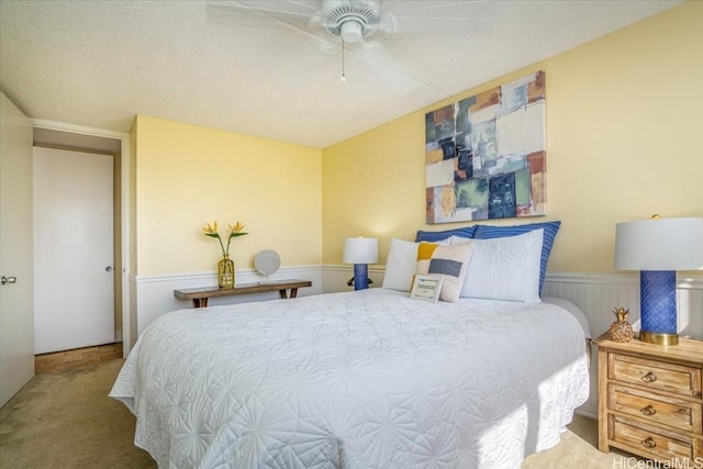 carpeted bedroom featuring ceiling fan and a textured ceiling