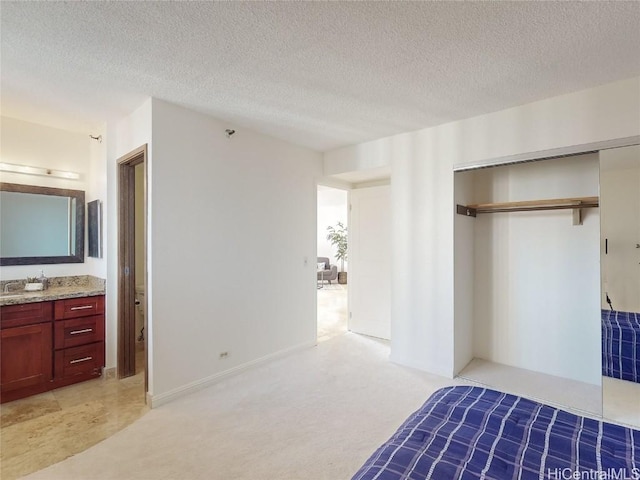 bedroom featuring ensuite bathroom, light colored carpet, a textured ceiling, and a closet