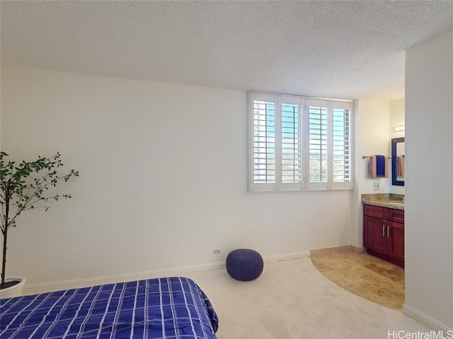 bedroom with carpet flooring, ensuite bathroom, and a textured ceiling