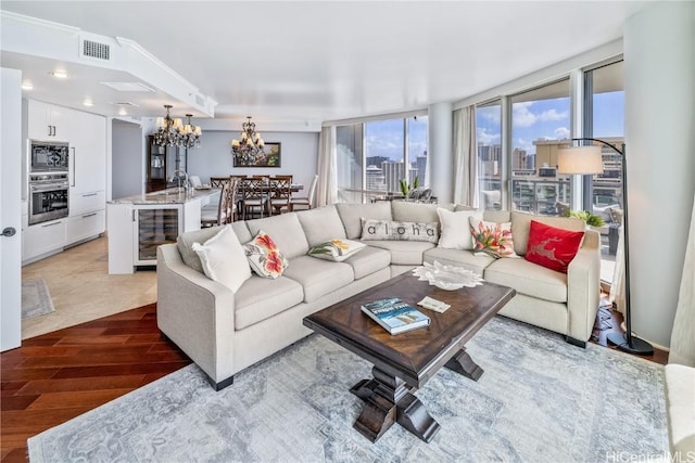 living room with a chandelier, a wall of windows, hardwood / wood-style flooring, and beverage cooler