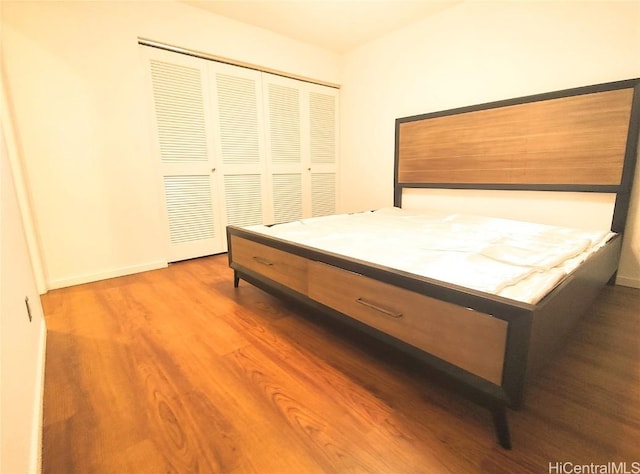 bedroom with a closet, baseboards, and wood finished floors