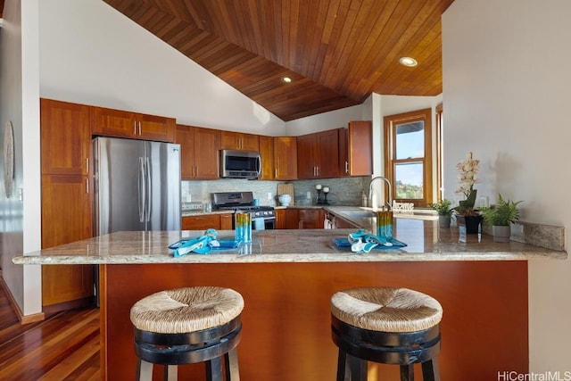 kitchen with a breakfast bar, lofted ceiling, kitchen peninsula, wood ceiling, and stainless steel appliances