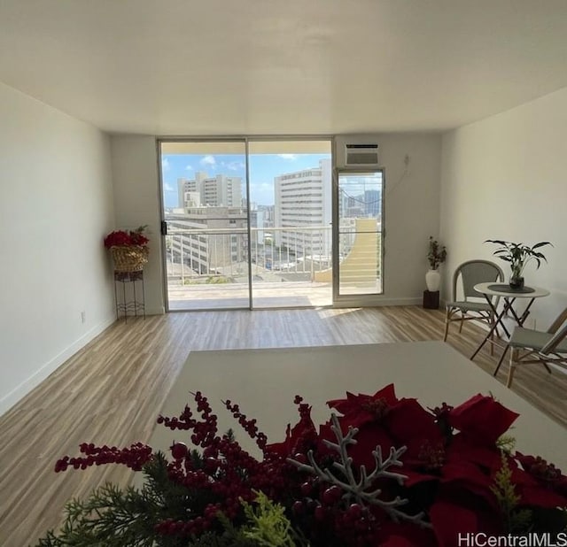 unfurnished room with a wall mounted AC, hardwood / wood-style floors, and plenty of natural light