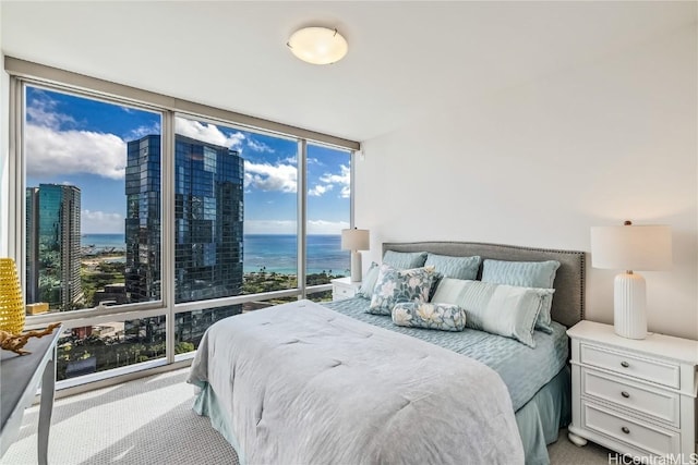 bedroom featuring floor to ceiling windows, a water view, and light carpet