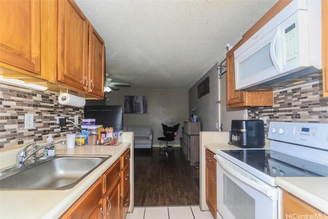 kitchen with a textured ceiling, sink, light hardwood / wood-style floors, and white appliances