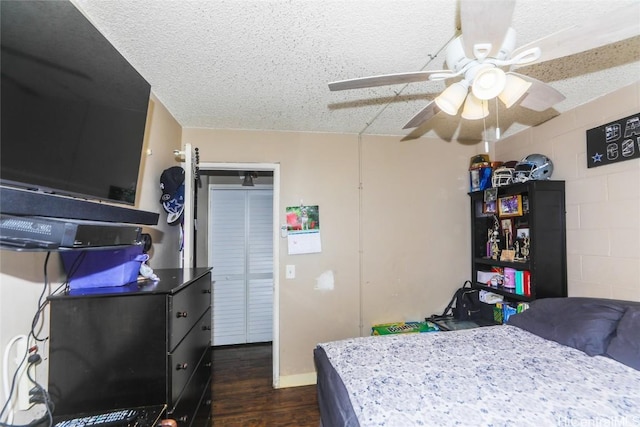 bedroom with ceiling fan, dark wood-type flooring, and a textured ceiling